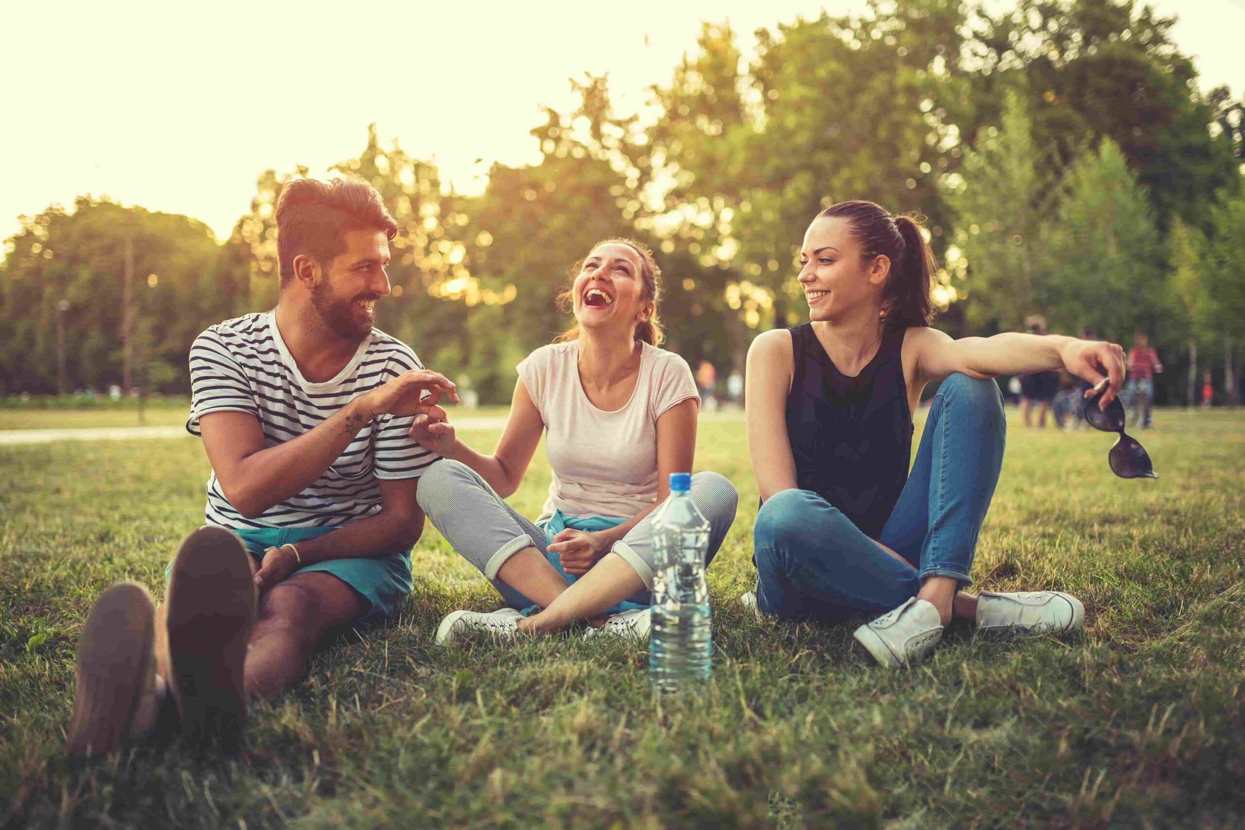 three students sitting on the green grass enjoying the sunny day